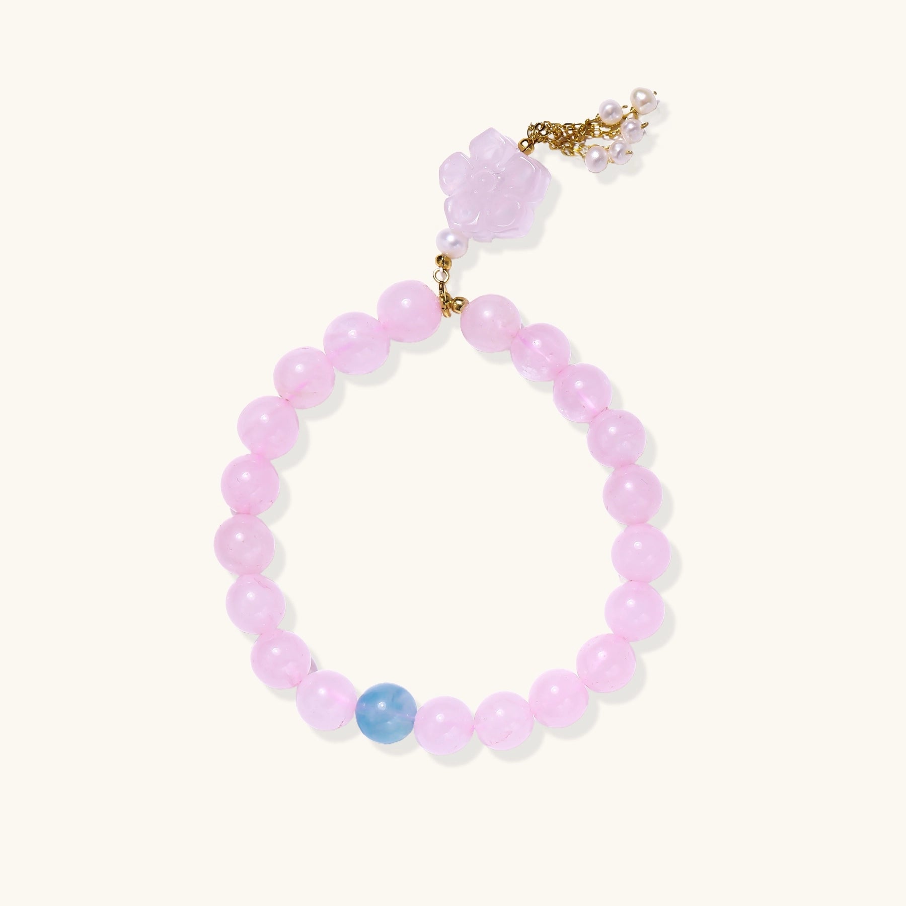 Beaded bracelet with pink rose quartz stones, blue aquamarine accent, and pearl chain details on white background