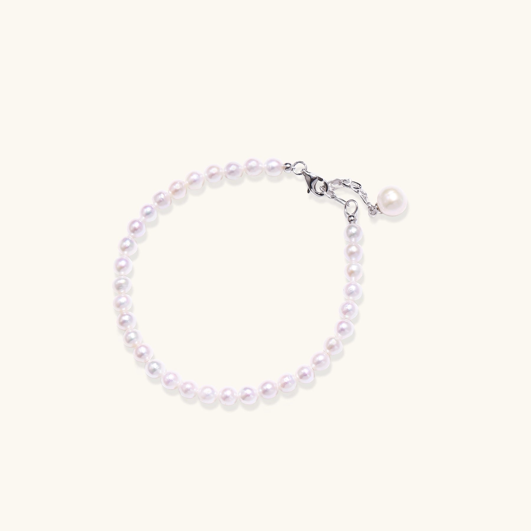 Delicate sterling silver bracelet with small freshwater pearls and adjustable chain on neutral background.