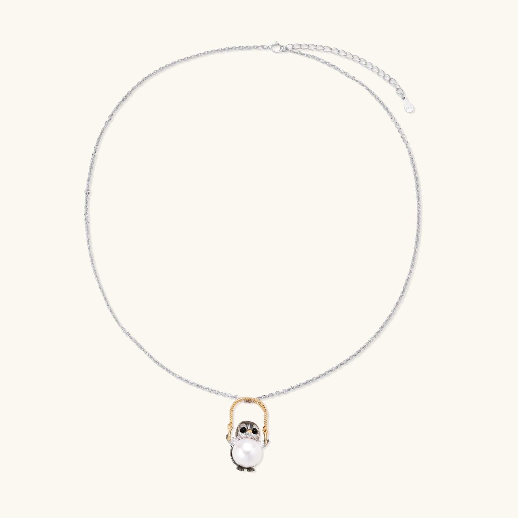 Silver owl pendant holding a round freshwater pearl on an adjustable chain against white background