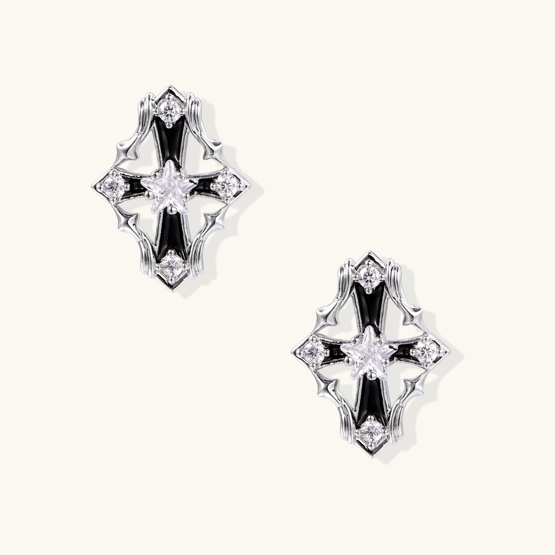 Pair of gold-plated cross earrings with clear zirconia crystals and silver posts on neutral background.