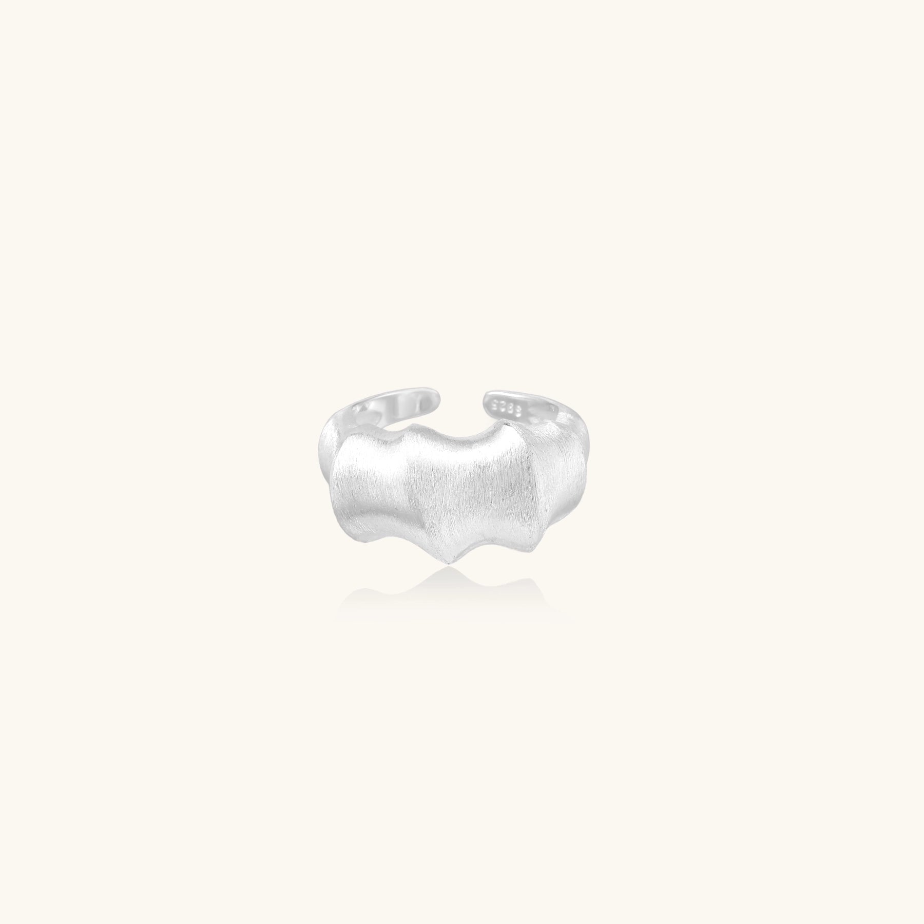 Chunky sterling silver ring with organic flowing design and brushed matte finish on neutral background