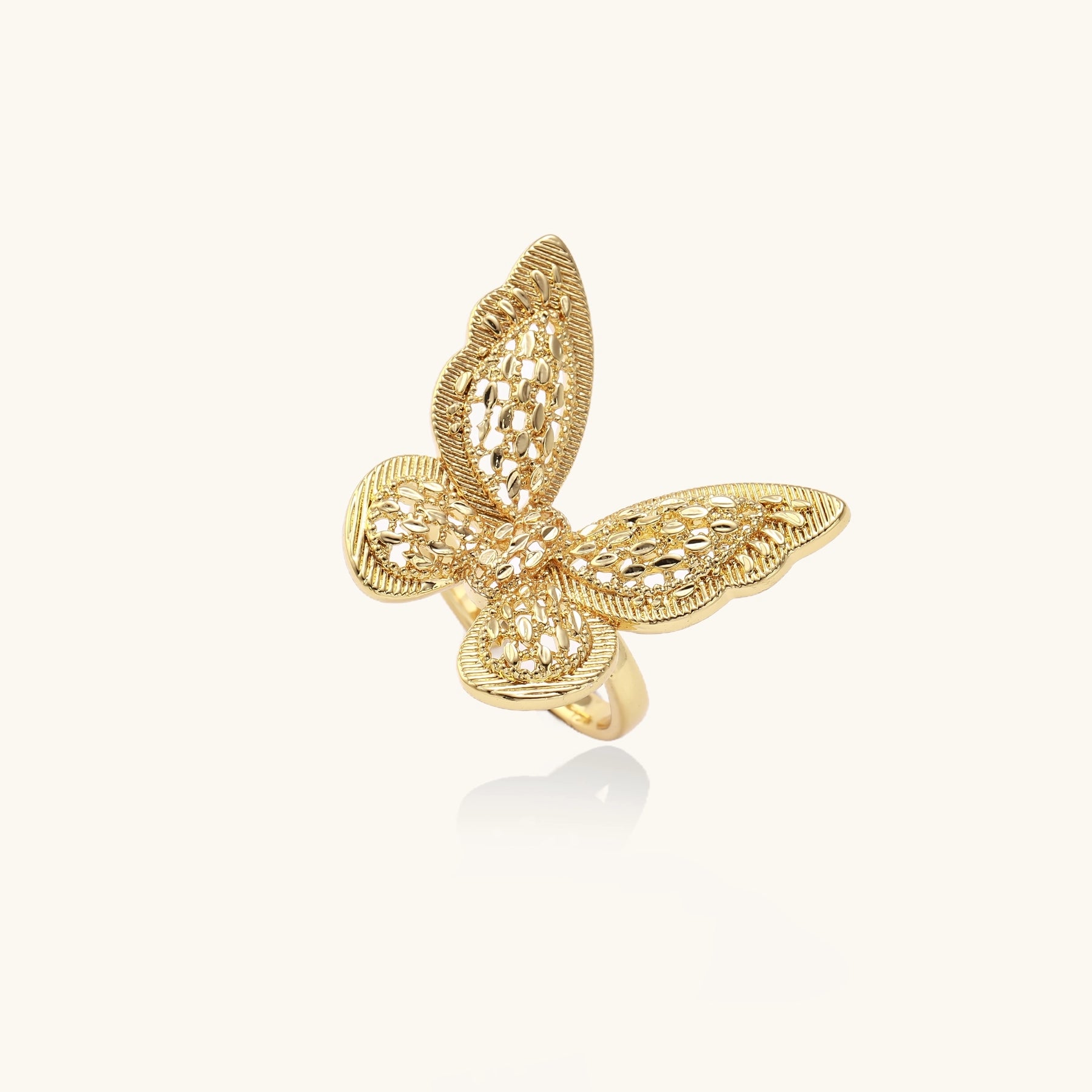 Adjustable gold-plated brass butterfly ring with intricate filigree cutout patterns and cubic zirconia accents on white background.