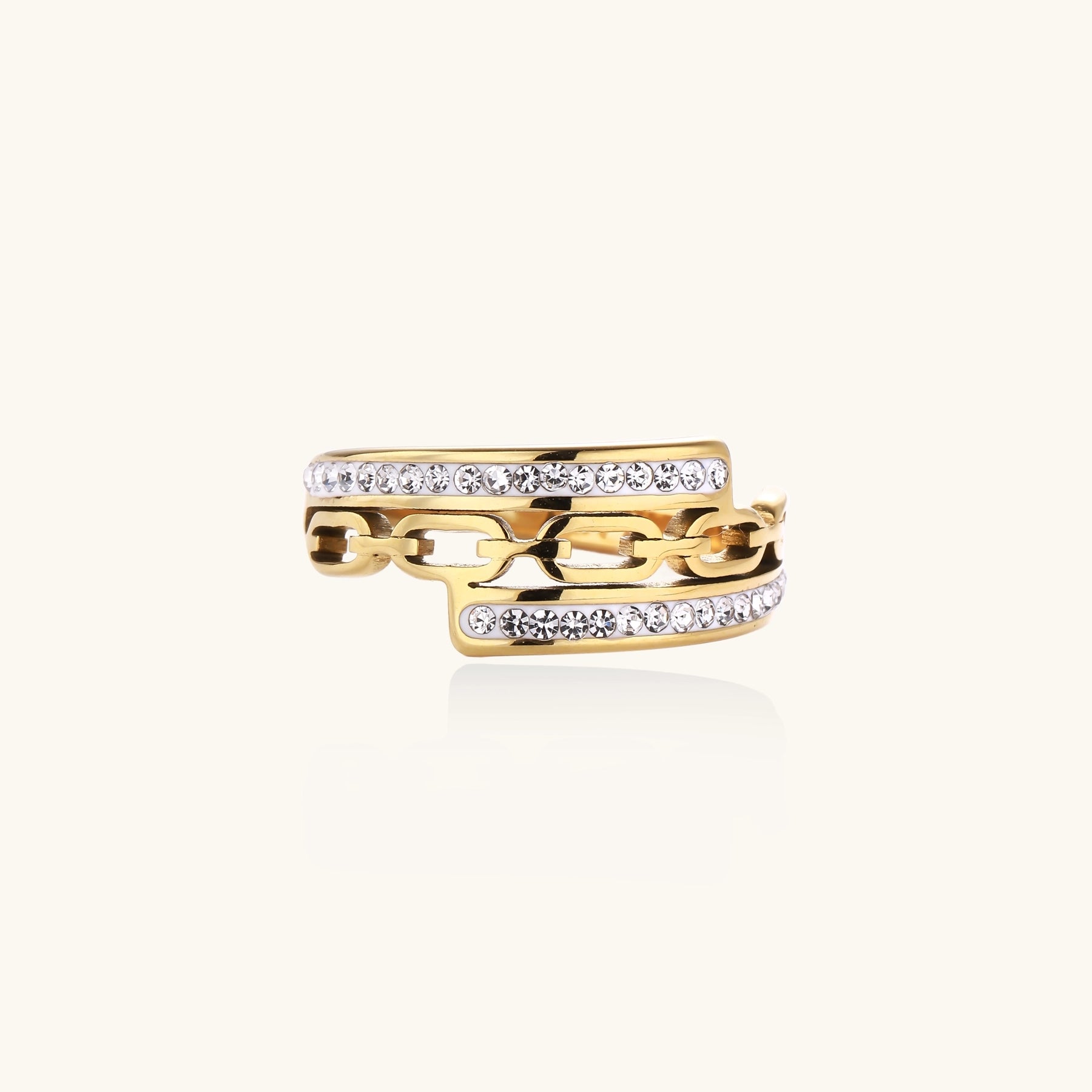 Gold-plated chain-link ring with rhinestone rows on cream background, showing bold geometric design and sparkling details.