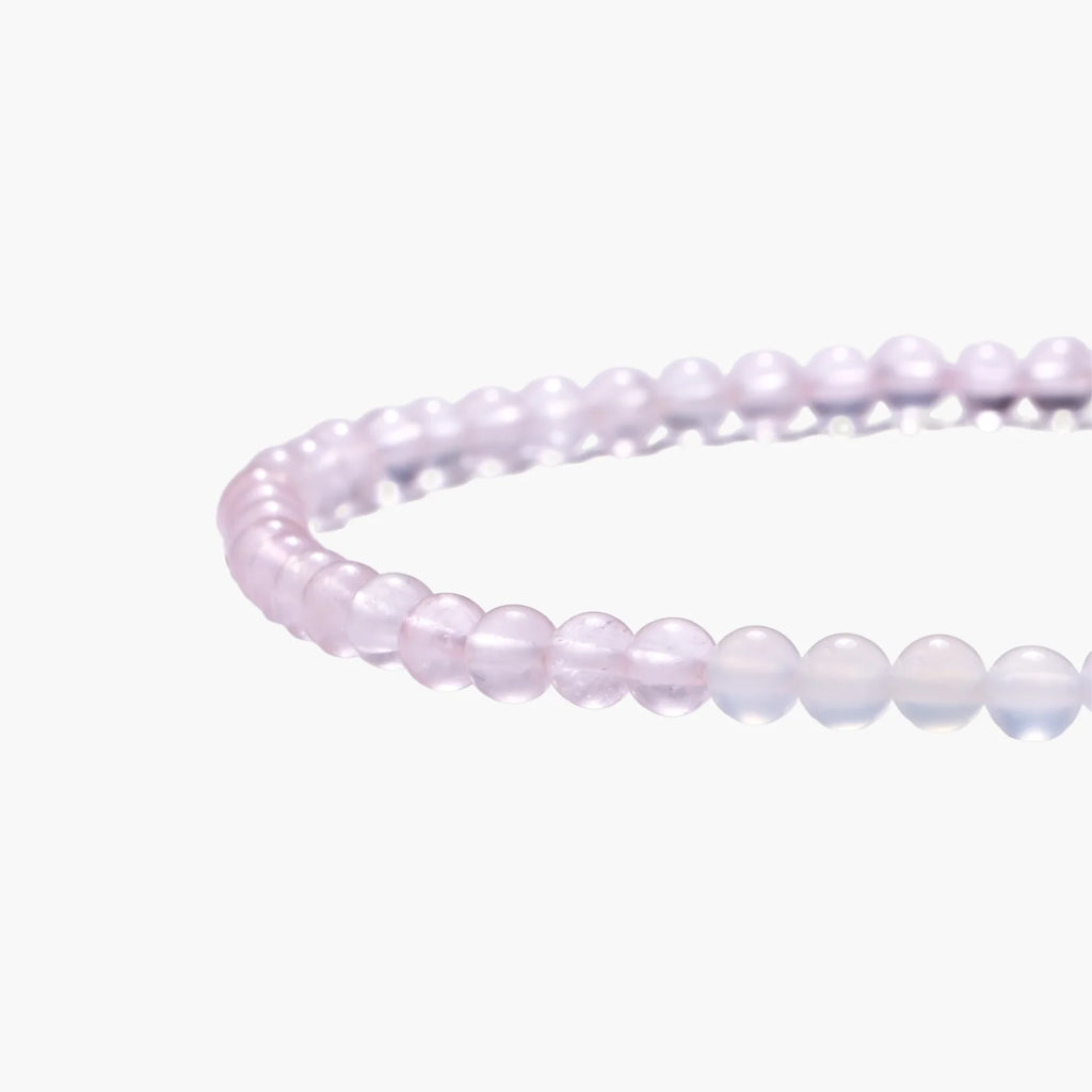 Double-wrap lavender beaded bracelet with rose quartz, pearls, gold vermeil charm and pink tassel on white background.