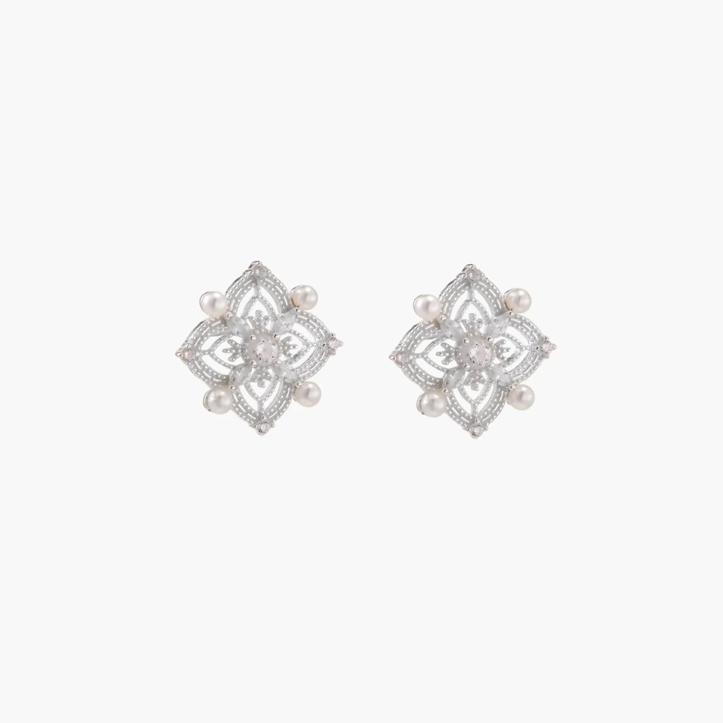 Ornate sterling silver stud earrings with mandala-inspired filigree pattern and four freshwater pearls on beige background