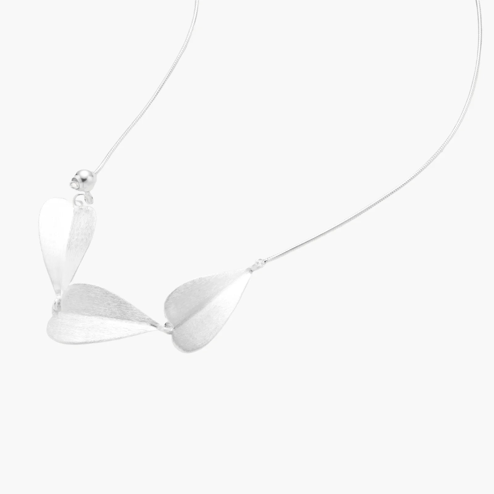 Minimalist sterling silver necklace with three brushed leaf-shaped pendants on delicate chain against white background