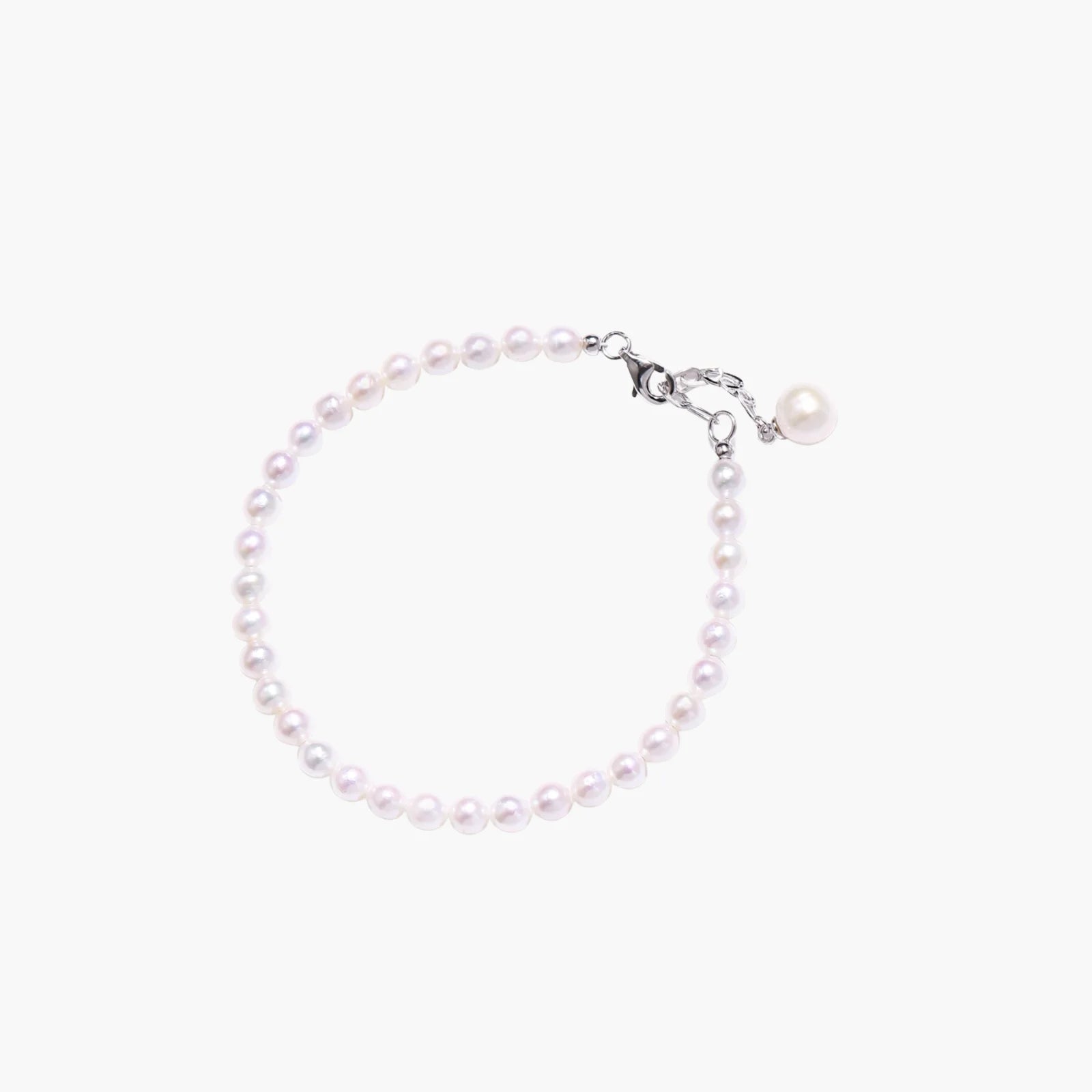 Delicate freshwater pearl bracelet with rhodium-plated silver clasp and single pearl drop charm on cream background