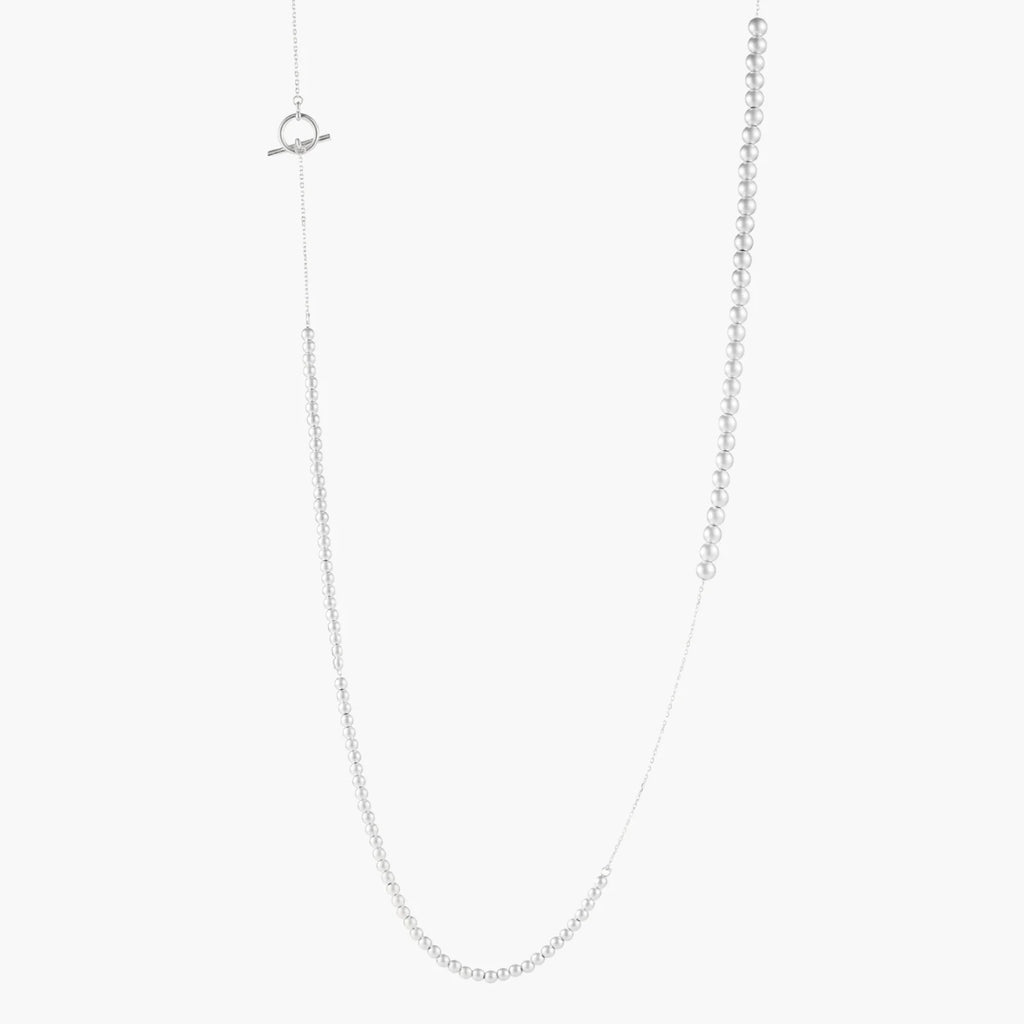 Long sterling silver beaded necklace with graduated sphere design, toggle clasp, and delicate chain extension on white background